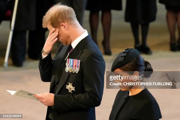 Britain's Prince Harry , Duke of Sussex, wipes away a tear as he pays his respects with Meghan , Duchess of Sussex inside Westminster Hall, at the...