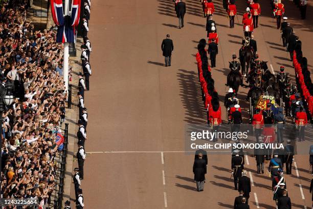 The coffin of Queen Elizabeth II, adorned with a Royal Standard and the Imperial State Crown and pulled by a Gun Carriage of The King's Troop Royal...