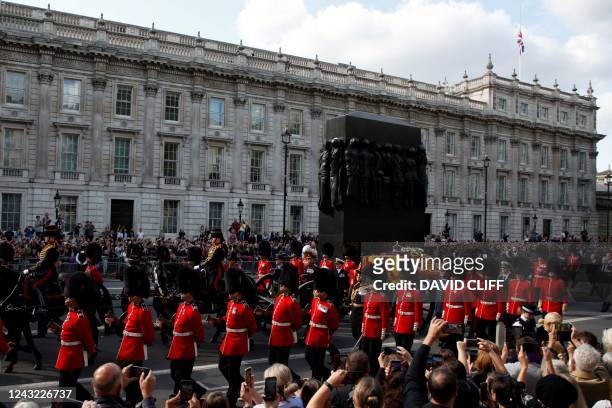 The coffin of Queen Elizabeth II, pulled by a Gun Carriage of The King's Troop Royal Horse Artillery, passes the The Women of World War II monument...