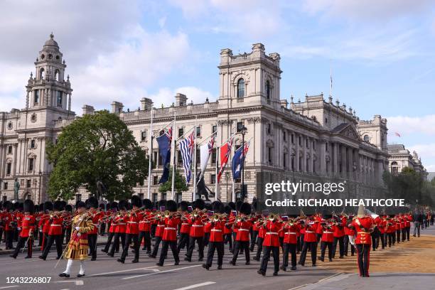 The Band of The Coldstream Guards march ahead of the coffin of Queen Elizabeth II, adorned with a Royal Standard and the Imperial State Crown and...