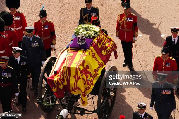 The coffin of Queen Elizabeth II, draped in the Royal Standard with the Imperial State Crown placed on top, is carried on a horse-drawn gun carriage...