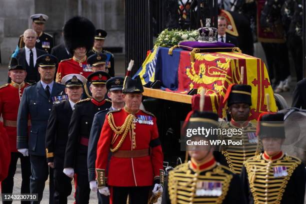 The coffin of Queen Elizabeth II, draped in the Royal Standard with the Imperial State Crown placed on top, is carried on a horse-drawn gun carriage...