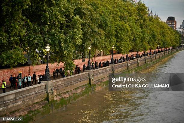 Members of the public queue on the pier between Westminster and Lambeth Bridge in London on September 14, 2022 to view the coffin of Britain's Queen...