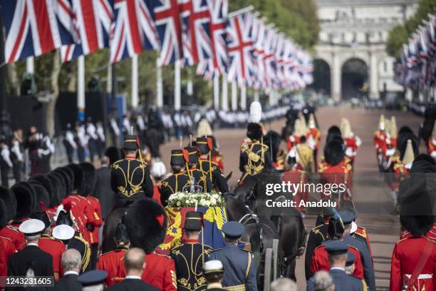 The coffin of Queen Elizabeth II, borne on a gun carriage and adorned with a Royal Standard and the Imperial State Crown, travelling in a ceremonial...