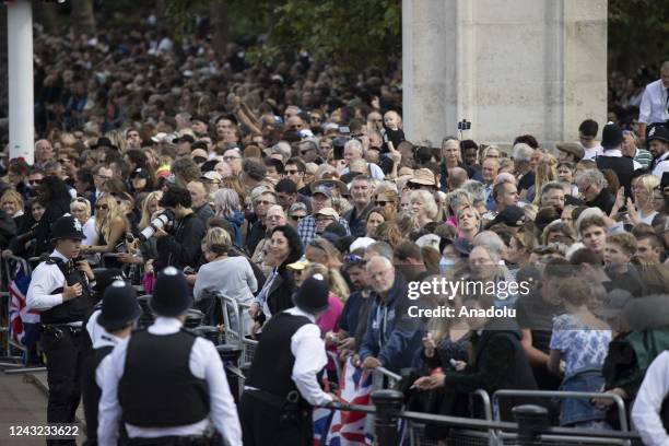 People queue on the road from where the coffin of Queen Elizabeth II, adorned with a Royal Standard and the Imperial State Crown is pulled by a Gun...