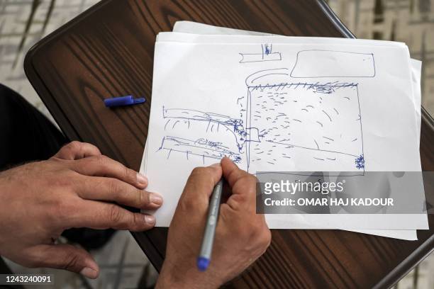 Mutassem Abd al-Sater, 42-year-old former inmate at Sednaya prison, draws a rudimentary sketch of the prison plan during an interview at his house in...