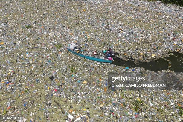 In this aerial view men collect waste of plastic residues, glass and other materials at the Cerron Grande reservoir in Potonico, El Salvador, on...