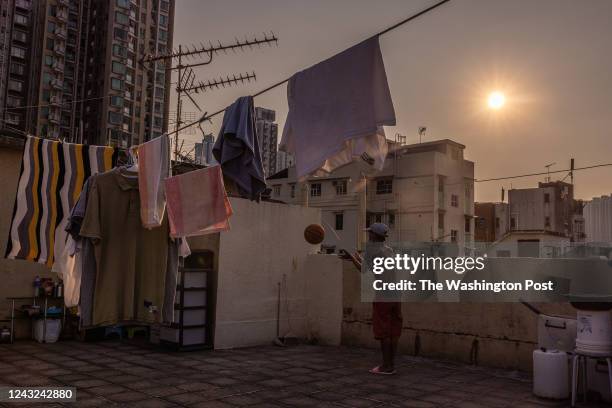 Neighbour plays basketball at the rooftop where the Aus family live in the Sham Shui Po area of Hong Kong on July 28, 2022.