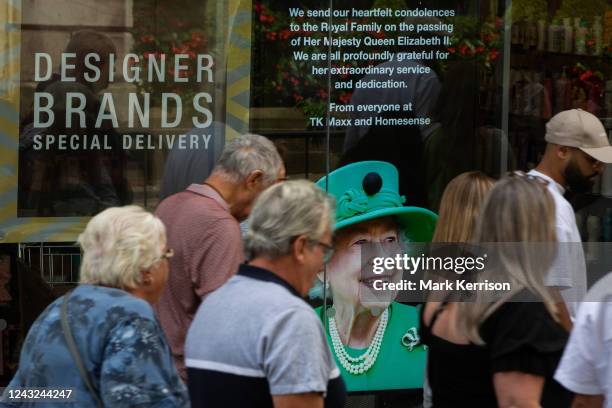 Members of the public pass a tribute to Queen Elizabeth II displayed in a shop window on 14th September 2022 in Windsor, United Kingdom. Queen...