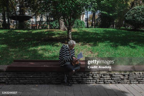 Ukrainian woman reads a book as she is sitting on a bench at a street as the Russia - Ukraine war continues in Kiev, Ukraine on September 14, 2022....