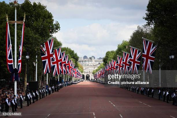 September 2022, Great Britain, London: Police officers stand on the edge of the street "The Mall" in front of waiting spectators before the start of...