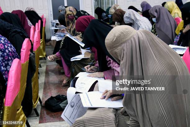 Afghan burqa-clad women take an entrance test at Mamon Tahiri institute in Kandahar on September 15, 2022.