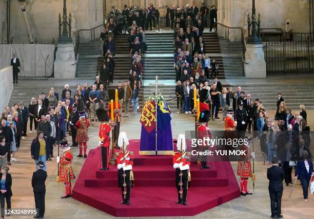 Members of the public file past the coffin of Queen Elizabeth II, draped in the Royal Standard with the Imperial State Crown and the Sovereign's orb...