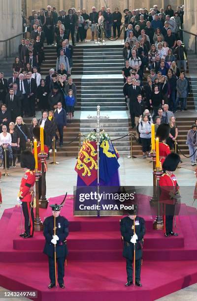 Members of the public file past the coffin of Queen Elizabeth II, draped in the Royal Standard with the Imperial State Crown and the Sovereign's orb...