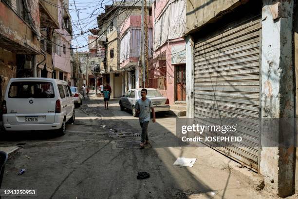 People walk along a street that was laden with corpses 40 years earlier during the Lebanese Civil War's Sabra massacre, at the Sabra camp for...
