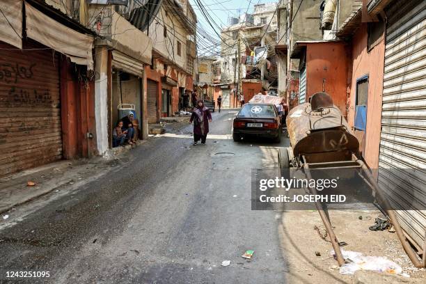 People walk along a street that was laden with corpses 40 years earlier during the Lebanese Civil War's Sabra massacre, at the Sabra camp for...