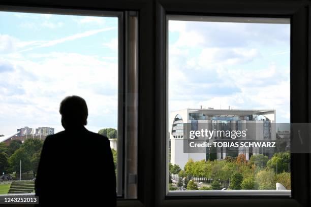 Man looks out of a window at the Reichstag building towards the Chancellery in Berlin on September 15, 2022.