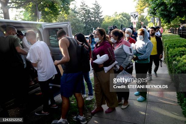 Migrants from Venezuela, who boarded a bus in Texas, wait to be transported to a local church by volunteers after being dropped off outside the...