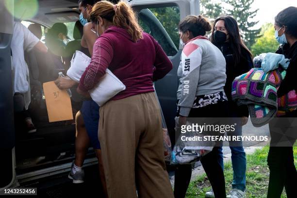 Migrants from Venezuela, who boarded a bus in Texas, wait to be transported to a local church by volunteers after being dropped off outside the...