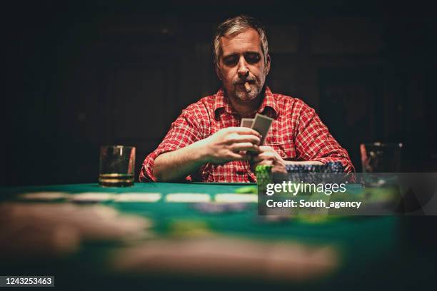 man playing poker in dark room at night - poker table stock pictures, royalty-free photos & images