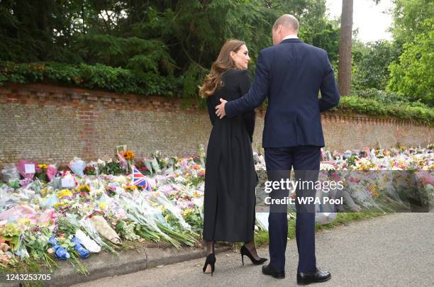 William, Prince of Wales and Catherine, Princess of Wales, speak while taking a look at floral tributes, following the death of Britain's Queen...
