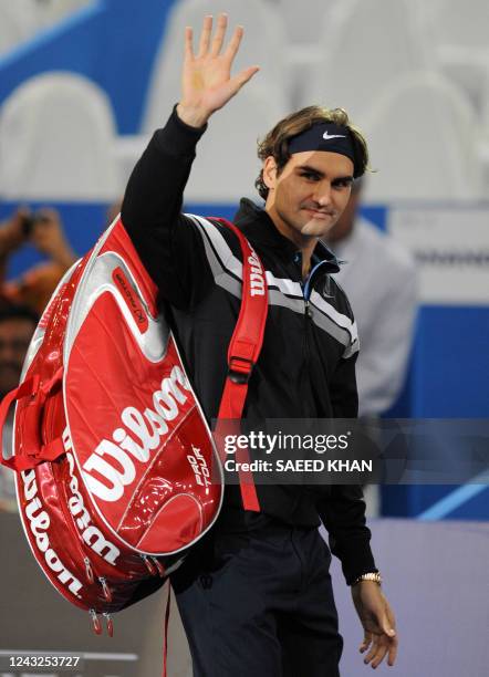 Roger Federer of Switzerland waves as he enters the court to play an exhibition match against James Blake of USA in Kuala Lumpur on November 18,...