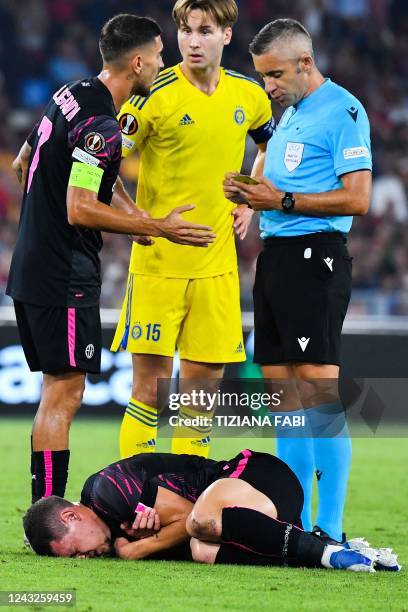 Romanian referee Radu Petrescu prepares to give a red card to HJK Helsinki's Finland's defender Miro Tenho for fouling AS Roma's Italian forward...