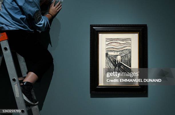 Museum worker installs a Museum label for a lithography of "The Scream" by Norwegian painter Edvard Munch during the preview of the "Edvard Munch. A...