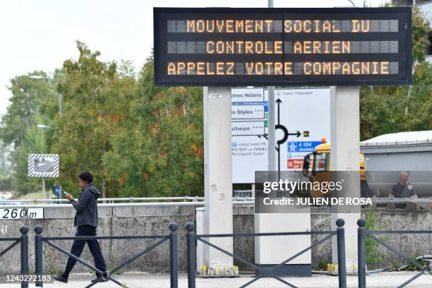 This photograph taken on September 16 shows a pedestrian walking past an information pannel translating into "social movement of air traffic control,...