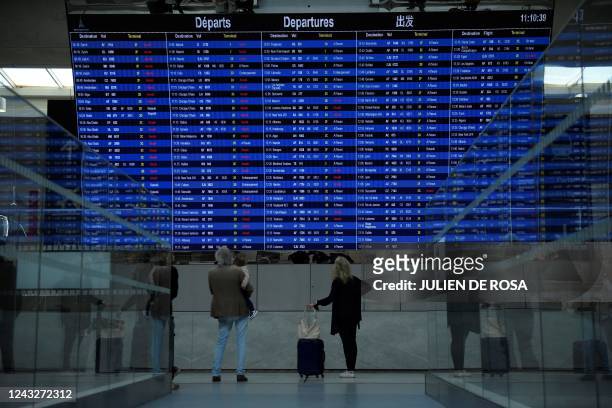 This photograph taken on September 16 shows travellers looking at the departure information panel of the Terminal 2 of the Roissy-Charles de Gaulle...