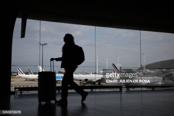Traveller walks in the Terminal 2 corridors of the Roissy-Charles de Gaulle airport with Air France airplanes in the background, in the northeastern...