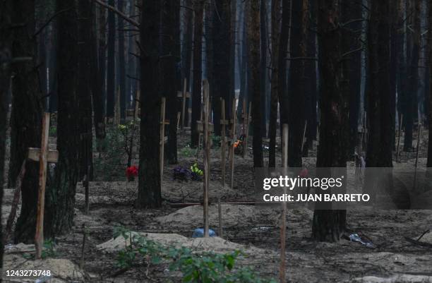 This photograph taken eastern Ukraine on September 16, 2022 shows crosses at a burial site in a forest on the outskirts of Izyum. - Ukraine said on...