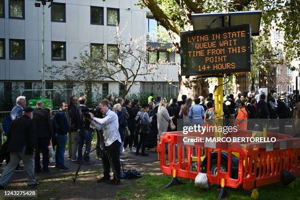 Digital sign board displays the queueing time as members of the public stand in the queue at Southwark Park, as they wait in line to pay their...