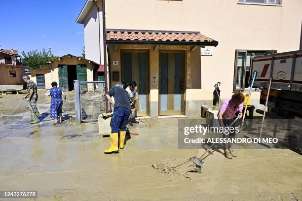 People clean outside a flooded house following an overnight rain bomb in Pianello di Ostra, Ancona province, on September 16, 2022. - At least ten...