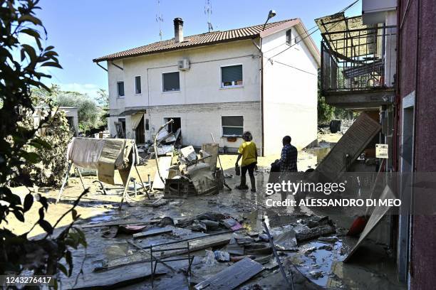 People clean outside a flooded house following an overnight rain bomb in Pianello di Ostra, Ancona province, on September 16, 2022. - At least ten...