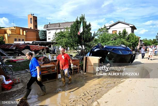 People clean a street outside flooded houses following an overnight rain bomb in Pianello di Ostra, Ancona province, on September 16, 2022. - At...