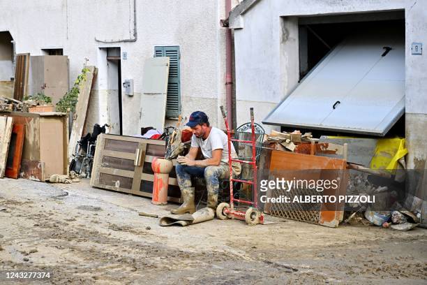 Man rests in front of a flooded house following an overnight rain bomb in Pianello di Ostra, Ancona province, on September 16, 2022. - At least ten...