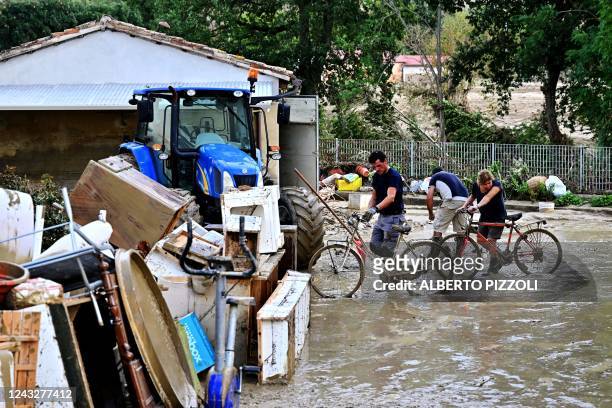 Residents fix their bicycles in front of a flooded house following an overnight rain bomb in Pianello di Ostra, Ancona province, on September 16,...
