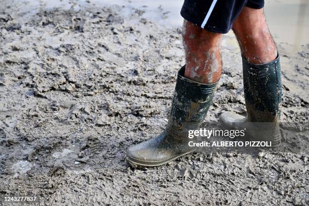 Man wearing rubber boots walks in a flooded street following an overnight rain bomb in Pianello di Ostra, Ancona province, on September 16, 2022. -...