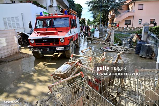 People clean a flooded street following an overnight rain bomb in Pianello di Ostra, Ancona province, on September 16, 2022. - At least ten people...