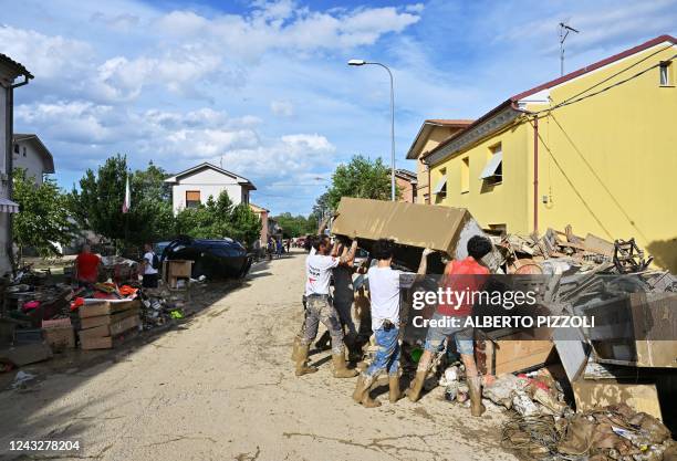 People clean a flooded street following an overnight rain bomb in Pianello di Ostra, Ancona province, on September 16, 2022. - At least ten people...