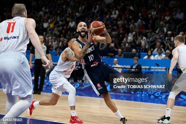 France's captain Evan Fournier gets past Poland's A.J. Slaughter during the FIBA Eurobasket 2022 semi-final basketball match between Poland and...