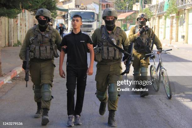 Israeli forces detain a boy named Vajdi al-Rajbi custody as they and confiscated his bicycle after they raided Palestinian locations in Hebron, West...