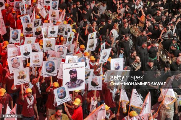 Shiite Muslim devotees of Iraq's Hashed al-Shaabi paramilitaries raise pictures depicting their late slain commander Abu Mahdi al-Muhandis, and the...