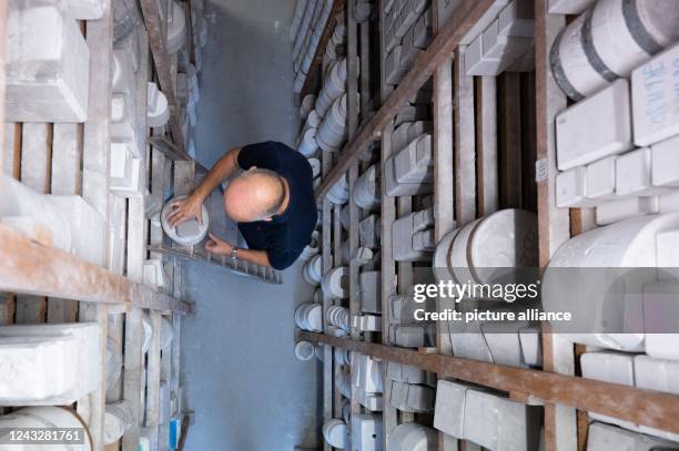 September 2022, Saxony, Meißen: Sven Beyer, head of mold making, stands on a ladder in the mold archive at Porzellanmanufaktur Meissen. Photo:...