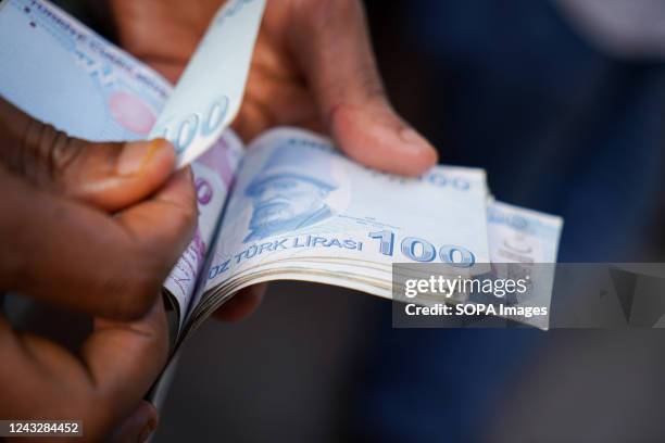 Man counts 100 Turkish lira banknotes in Ankara City.