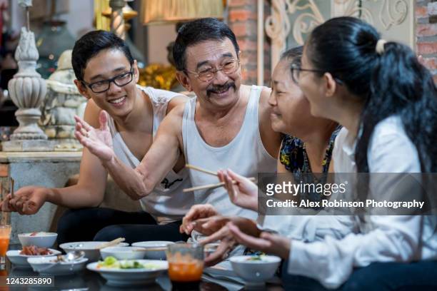a senior married couple eating dinner with their adult children in their apartment in vietnam - vietnamese culture ストックフォトと画像