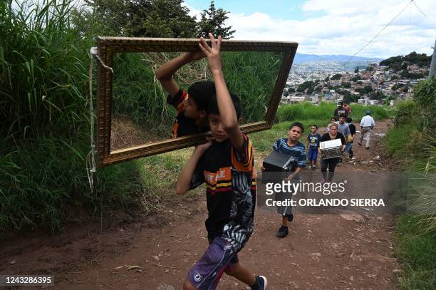 Children carry belongings as they leave Colonia Guillen, a neighbourhood northwest of Tegucigalpa, declared uninhabitable by authorities due to...