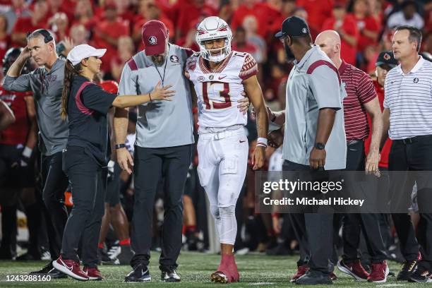 Jordan Travis of the Florida State Seminoles is assisted off the field during the first half against the Louisville Cardinals at Cardinal Stadium on...