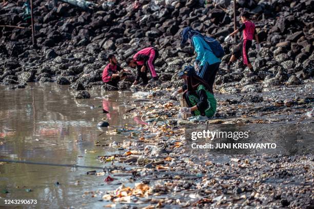 Students and environment activists take part in a clean-up effort to remove wastes and garbages from a beach in Surabaya on September 17 during World...